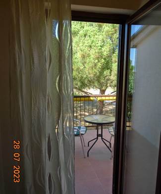A window with a curtain and a table outside

Description automatically generated