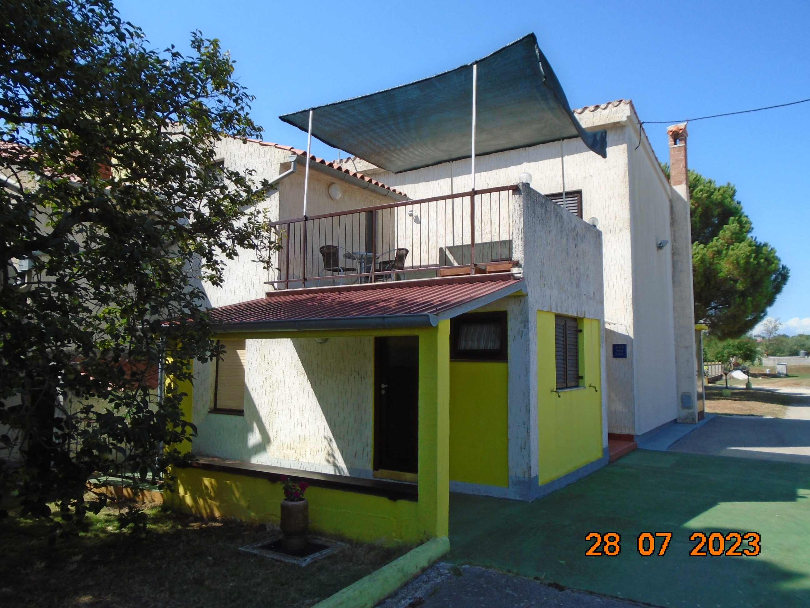 A house with a yellow wall and a green lawn

Description automatically generated